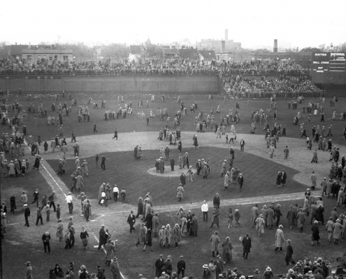 Fans depart Wrigley Field via the diamond. Note the temporary bleachers set up beyond the left field wall on Waveland Avenue as well as the “jury box” section in left-center field.