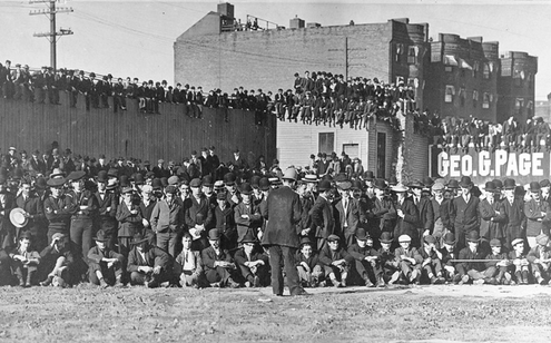 Boston rooters gather in center field, on rooftops, and seated on the outfield fence to see the Boston Americans play the New York Highlanders (Yankees) in a pivotal doubleheader in 1904.