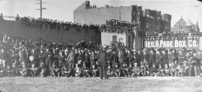 Boston rooters gather in center field, on rooftops, and seated on the outfield fence to see the Boston Americans play the New York Highlanders (Yankees) in a pivotal doubleheader in 1904.