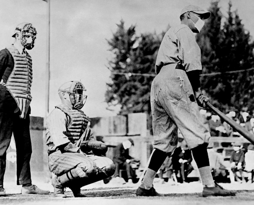 John “Beans” Reardon, left, wearing a flu mask underneath his umpire’s mask, prepares to call a pitch in a California Winter League game on January 26, 1919, in Pasadena, California. During a global influenza pandemic, all players and fans were required by city ordinance to wear facial coverings at all times while outdoors. The catcher and batter’s identities are unconfirmed, but the best available evidence suggests it might be Truck Hannah behind the plate and Rube Ellis at bat.