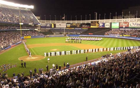 A large American flag is unfurled on the outfield by SUNY Maritime Academy cadets as the Yankees and Devil Rays are joined by members of the New York City Fire Department, EMS and Police Department during ceremonies honoring the victims of the World Trade Center terrorist attack. (COURTESY OF MLB.COM)